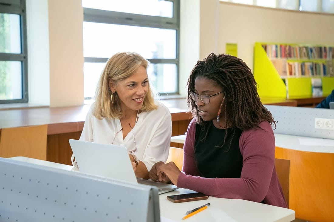 Two students happily collaborate with a laptop.