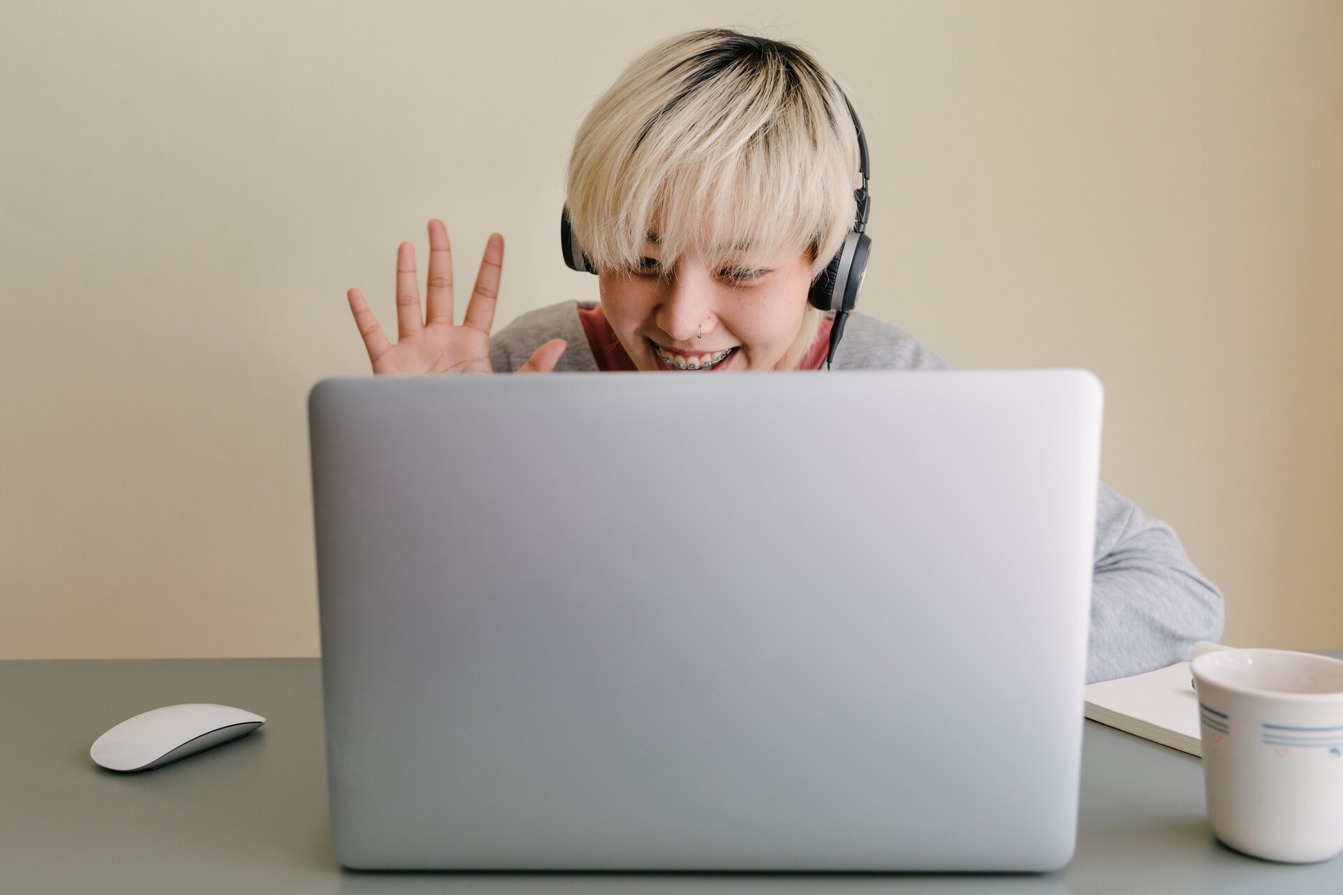 Smiling teacher waves during an online lesson from her computer.
